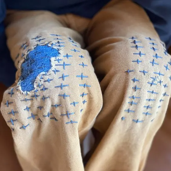 A close-up photograph of medical compression boots with blue stitching and a blue padded section being worn on a person's legs.