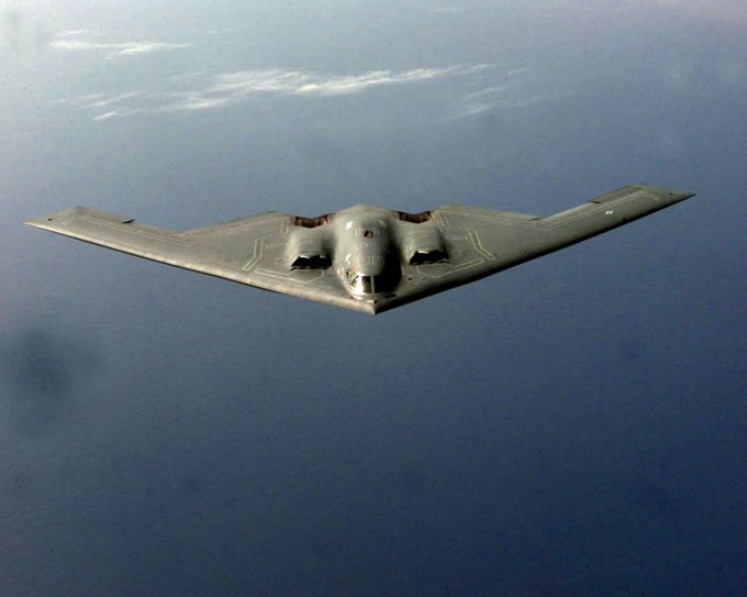 A B-2 Spirit stealth bomber flies through a clear blue sky, its sleek, angular bat-wing design evoking the elusive and decentralized nature of "Nakamoto Consensus," the foundational protocol behind Bitcoin's secure, trustless network.