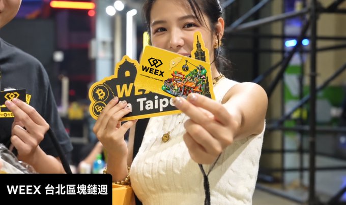A woman holding up yellow WEEX promotional cards at an event, with a caption reading "WEEX 台北區塊鏈週" (WEEX Taipei Blockchain Week).