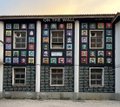 A dark building facade is covered with numerous framed pictures or artwork displayed in its windows, with the watermark "FLICKR" visible.