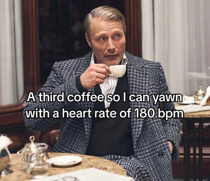 A meme featuring a man in a houndstooth coat sipping coffee, captioned: 'A third coffee so I can yawn with a heart rate of 180 bpm.'