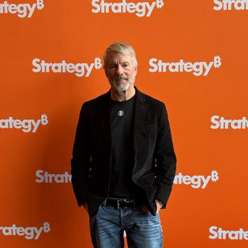 Michael Saylor, co-founder and executive chairman of Strategy (formerly MicroStrategy), stands in front of an orange backdrop featuring the "Strategy" company logo with the Bitcoin "₿" symbol. The image relates to the post by visually identifying Saylor as the leader of Strategy, which just sold 1,690 $BTC for $108.6 million, bringing its total Bitcoin holdings to 840,447 BTC.