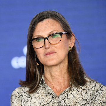 Cathie Wood, founder of ARK Invest, pictured wearing glasses and a snakeskin-pattern blouse, during a public appearance as her firm trims its $BMNR holdings.