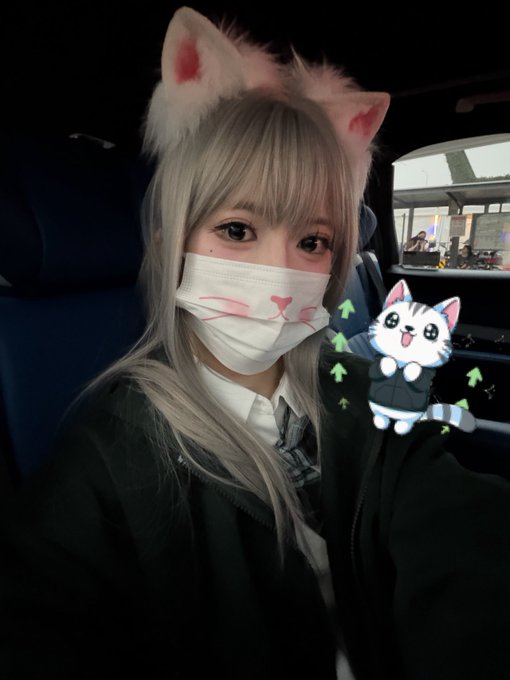 A young woman with cat ears and a cute cat-themed face mask takes a selfie inside a vehicle, with a digital cat sticker overlay on the image. The post mentions a "$HYPE" Hyperliquid Community Event, suggesting she may be heading to or from the event while embracing a playful feline aesthetic.