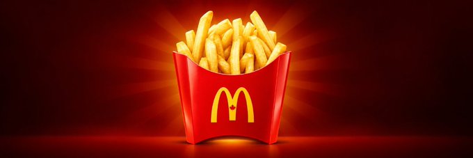 A red McDonald's french fries carton overflowing with fries, glowing against a dark red background.