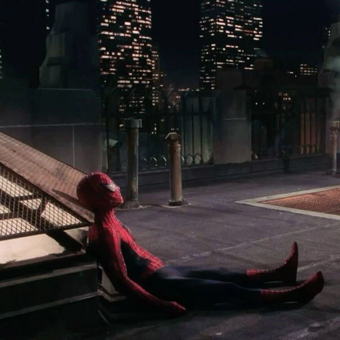 Spider-Man rests against steps on a city rooftop at night, looking out toward the illuminated skyline — a fitting "good morning" vibe for someone winding down before a weekend off.