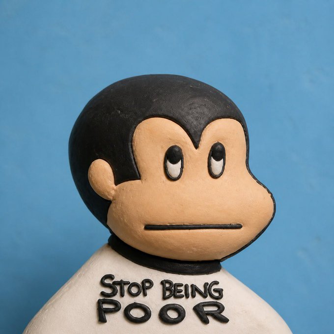 A clay sculpture of a cartoon-like figure with a black haircut and peach-colored face, featuring the text 'STOP BEING POOR' in black lettering across its white torso.