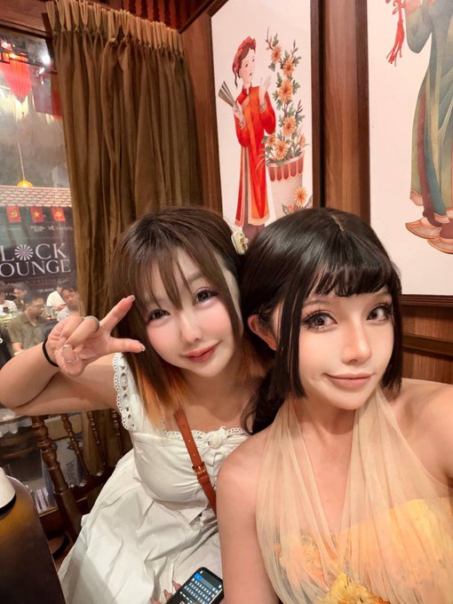 Two stylish women pose together for a selfie, one flashing a peace sign and the other smiling softly, with a "Block Lounge" sign visible in the background—likely attendees enjoying the Conviction 2026 event in Vietnam hosted by 9CAT Group.