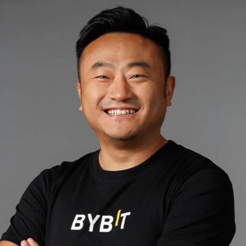 A portrait of a smiling East Asian man wearing a black t-shirt with the 'BYBIT' logo against a gray background.