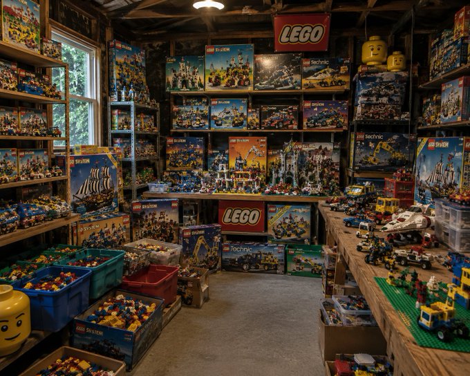 A cluttered room filled with vintage LEGO sets displayed on shelves and tables, including System, Technic, and Pirates boxes, with bins of loose bricks in the foreground.