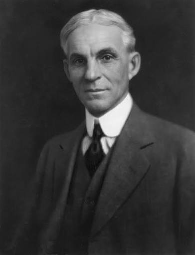 A black and white portrait photograph shows an older man in a formal suit and tie.