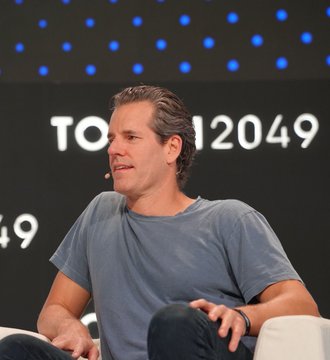 Cameron Winklevoss appears on a panel at the TOKEN2049 conference, captured mid-speech as he discusses the privacy features of Zcash compared to Bitcoin's transparent, decentralized ledger.