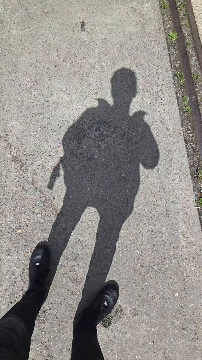 The image shows a person's shadow cast on the ground, which appears to be made of concrete or asphalt. The shadow is positioned near the center of the frame, with the person standing close by. The background features a train track running across the scene, suggesting that the photo was taken in an urban setting. The post includes text that reads "Solana Summit Germany in 28 seconds". This information might be related to the location or event captured in the image.