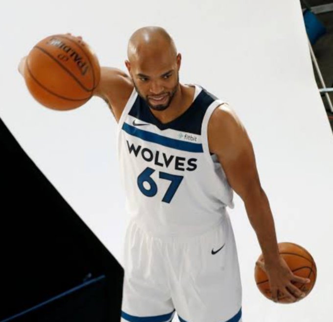 Basketball player wearing a white Minnesota Timberwolves jersey with the number 67, holding two Spalding basketballs while posing for a photo shoot.