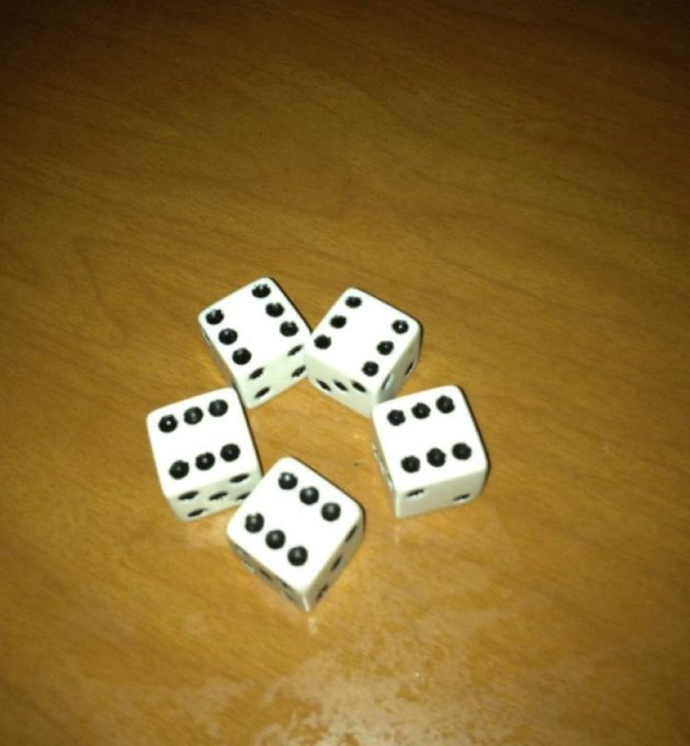 Five white dice with black dots arranged on a wooden surface.