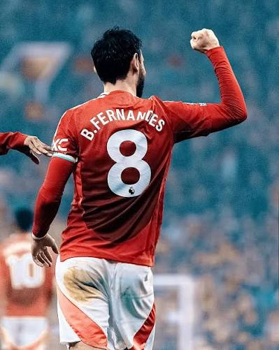 A soccer player wearing a red jersey with "B. FERNANDES" and the number "8" on the back, celebrating with a raised fist.