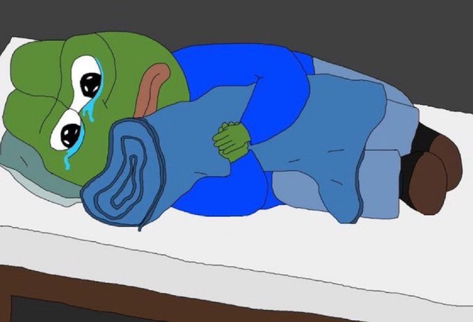 A cartoon illustration of a green-skinned character resembling Pepe crying tears while lying in bed under a blue blanket hugging a pillow.