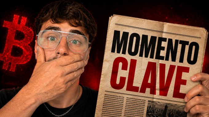 A shocked young man with glasses covers his mouth while holding a newspaper headline reading 'MOMENTO CLAVE' (Key Moment), with a red Bitcoin logo in the background.