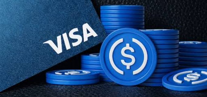 A close-up promotional image featuring a dark blue Visa card next to a stack of blue USDC stablecoin tokens with the dollar sign symbol.