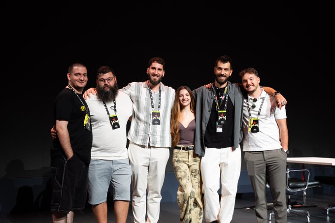 Six people pose together at a SuperteamBLKN event in Belgrade, with several wearing lanyards and one person wearing a "DRIK" lanyard, appearing to be team members or featured guests at the gathering.