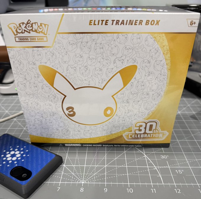 A Pokémon Trading Card Game Elite Trainer Box commemorating the 30th anniversary (30th Celebration), featuring a gold Pikachu silhouette and a background pattern of various Pokémon characters.