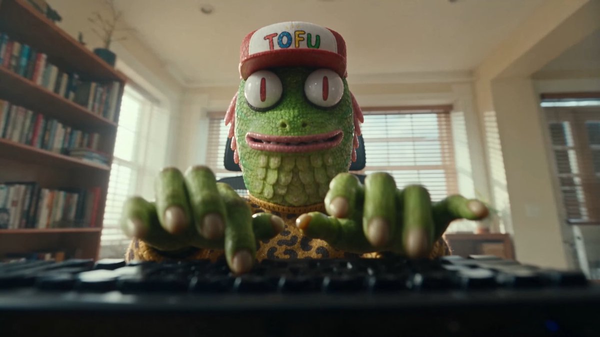 A green reptilian NFT character wearing a red and white cap with "TOFU" written in colorful letters, along with a yellow leopard-print shirt, is shown typing on a keyboard in a home office setting. The image ties into the post's promotion of the @creepz NFT project, with "Tofu" being a well-known character from the Creepz collection.