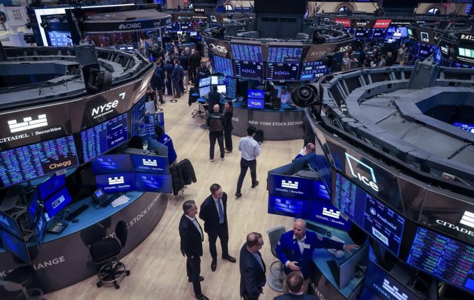 The image shows the bustling trading floor of the New York Stock Exchange (NYSE), featuring visible branding for "NYSE," "Citadel Securities," "CNBC," and stock tickers including "AQUA," "GGPI," and "Chegg," along with the "A.I.cca" logo on a blue display. While the post discusses cooling sentiment and falling XRP prices among retail investors, the image of the NYSE floor—home to major institutional activity and market makers like Citadel Securities—visually represents the "behind the scenes" institutional and regulated financial ecosystem where developments like RLUSD's expansion are taking place.