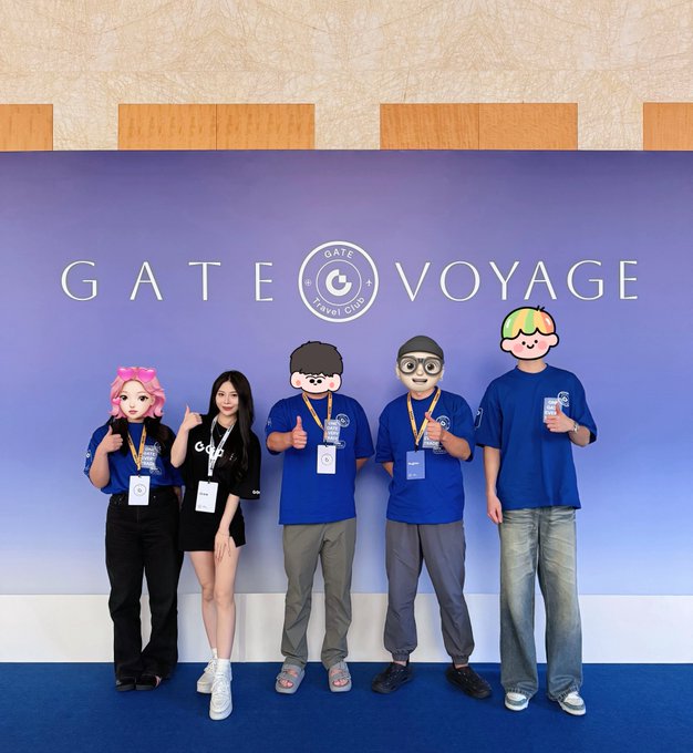 Five people pose in front of a 'GATE VOYAGE' Travel Club backdrop; two women wear blue shirts and three men wear blue shirts, with some faces covered by cartoon stickers.