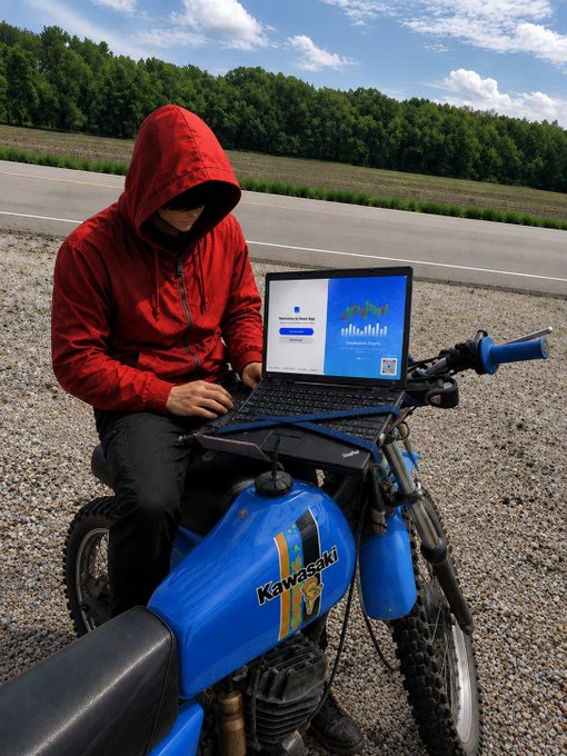 A person in a red hooded jacket with their face obscured, sitting on a blue Kawasaki dirt bike while using a laptop displaying a 'Machinery & Spare Parts' business website, on a roadside with trees in the background.