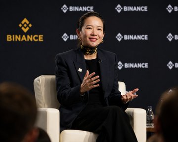 A woman, reportedly Binance co-founder He Yi, speaks during a panel at a Binance-branded event, gesturing with her hands as she discusses the platform's efforts in recovering over $8 billion in mistaken crypto transfers for users since 2021.