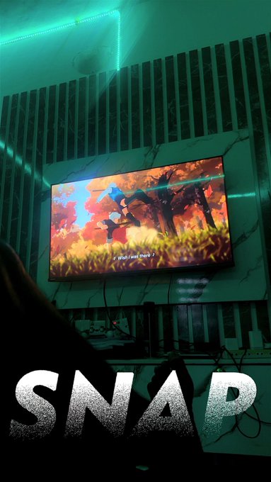 A dimly lit room with green ambient lighting features a TV screen displaying a vibrant animated scene with characters and the text 'What now? It's me!'. The word 'SNAP' is overlaid in large white letters across the bottom.