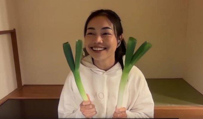 A smiling woman in a white hoodie holds up two leeks on either side of her face, playfully referencing the "leek" emoji—a cryptocurrency slang term for holding an asset through price volatility. The image humorously connects to the post's theme of steadfast loyalty through Monad's development and the dismissal of critics ("jeeters").