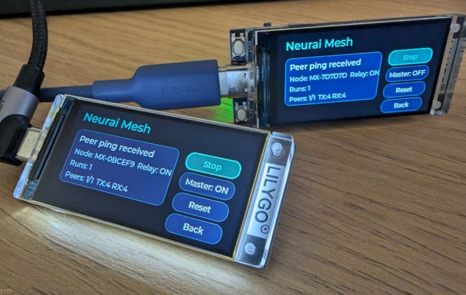 Two Lilygo T-display devices, connected via a USB cable, both showing a "Neural Mesh" interface with options for "Stop," "Master: ON," "Reset," and "Back," displaying "Peer ping received" details including node IDs, relay status, run count, and peer information. This setup demonstrates a practical Neurai DePIN use case, showcasing how these small networks can create private, encrypted messaging systems between devices.