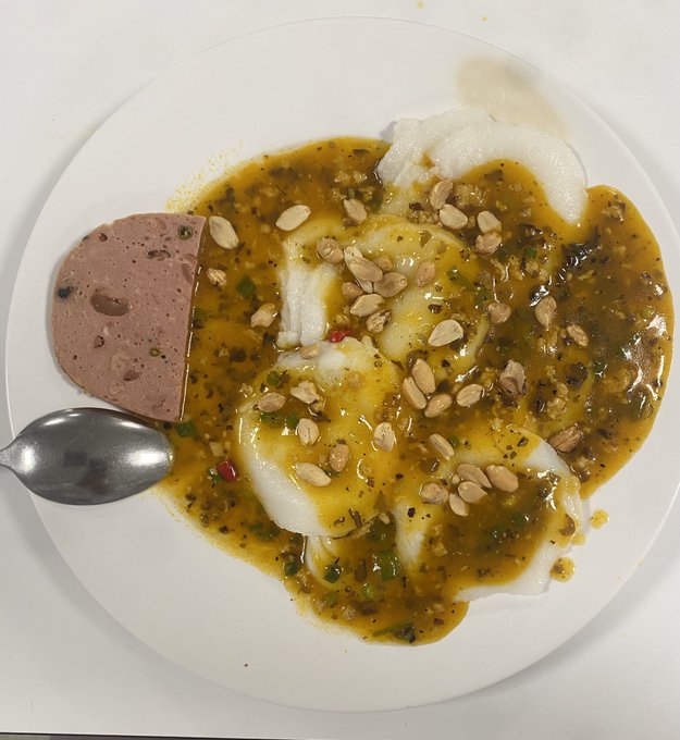 A simple meal featuring what appears to be fufu or a similar starchy food topped with a greenish-brown sauce and peanuts, served alongside a slice of liver pâté and a spoon on a white plate. The caption playfully contrasts this humble, traditional breakfast with anticipation for an incoming "Pay X cycle," hinting at hopes of financial relief soon.