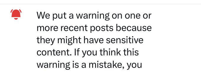 A screenshot showing a red bell icon next to text beginning 'We put a warning on one or more recent posts because they might have sensitive content.'