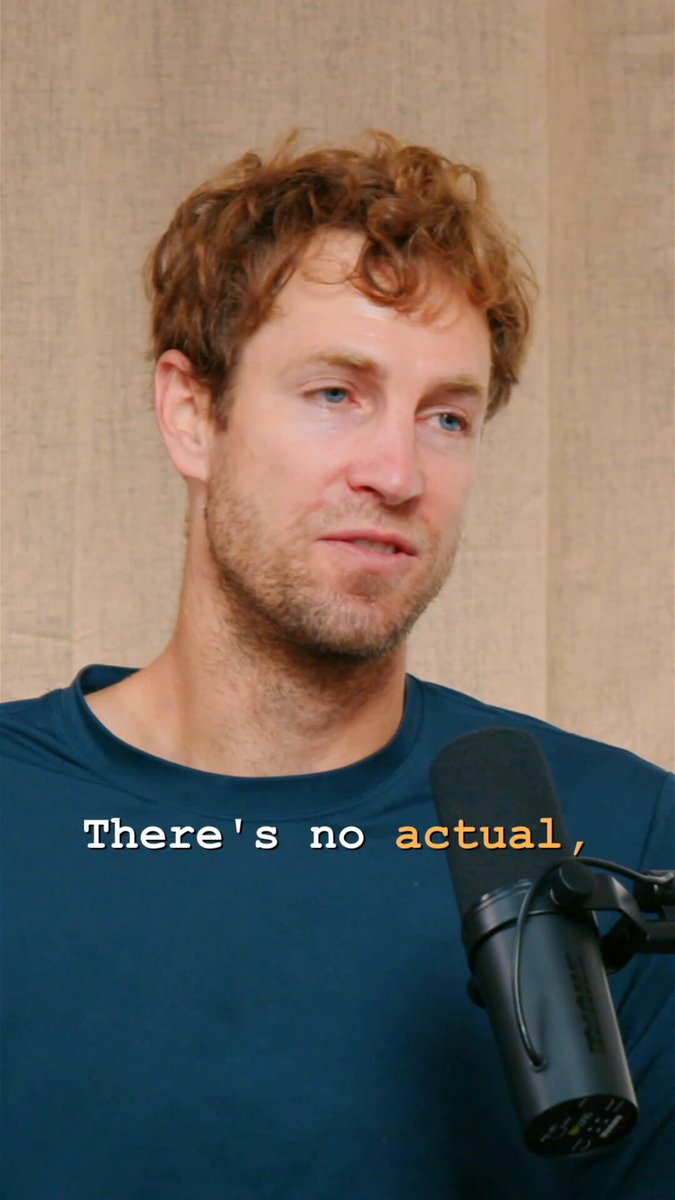 The image features a man wearing a blue shirt holding a microphone close to his face. The background appears to be a wall with a curtain hanging behind him. There is text that reads "There's no actual" written above the man, which seems to be related to the content of the image or the post it belongs to.