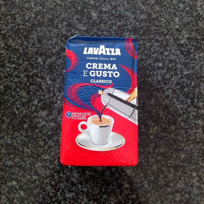 A 250g packet of Lavazza Crema e Gusto Classico ground coffee lying on a dark granite countertop.