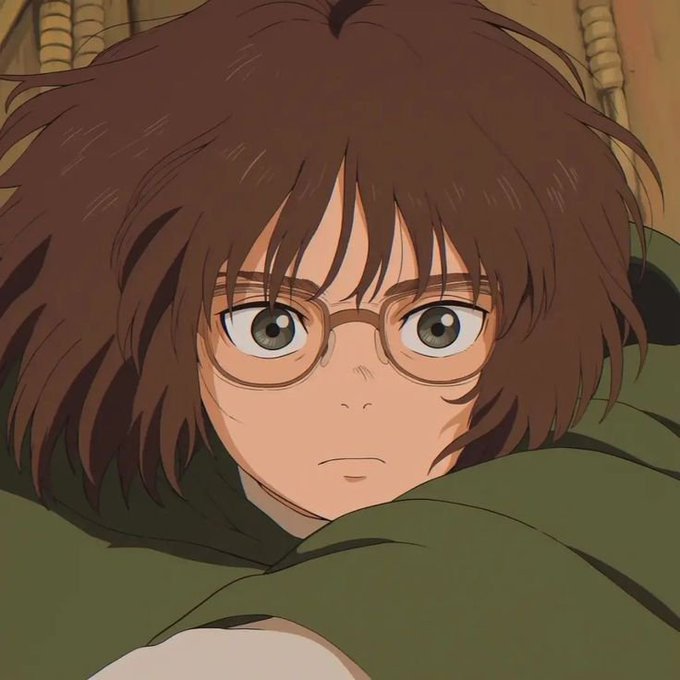 An anime-style illustration of a young woman with short brown hair and round glasses, wearing a green hooded cloak.