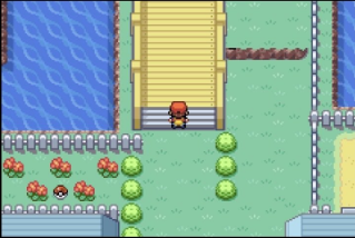 A pixel art screenshot from a Pokémon game showing a character standing at the top of wooden stairs near water, with red flowers and green bushes nearby.