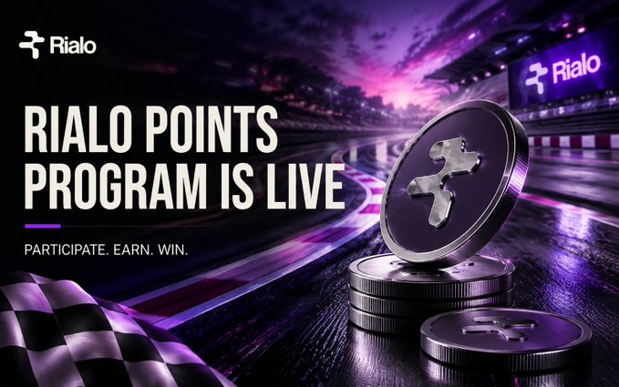 A promotional graphic for Rialo announcing 'RIALO POINTS PROGRAM IS LIVE' with the tagline 'PARTICIPATE. EARN. WIN.', featuring metallic coin tokens with the Rialo logo against a purple-lit racetrack background with a checkered flag.