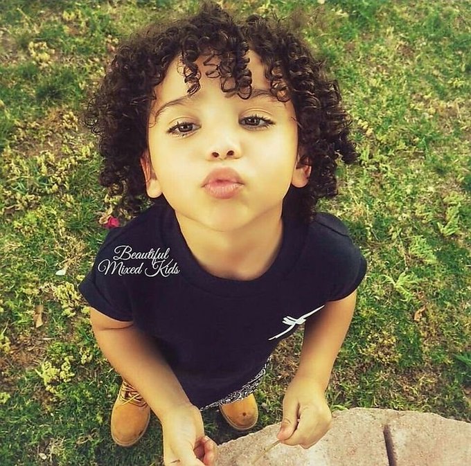 A young child with curly hair makes a pouty face while standing on grass, wearing a black shirt. The image bears the watermark "Beautiful Mixed Kids," suggesting the post is sharing a cute or endearing moment, with the caption hinting at plans to share more content with better movement tomorrow.