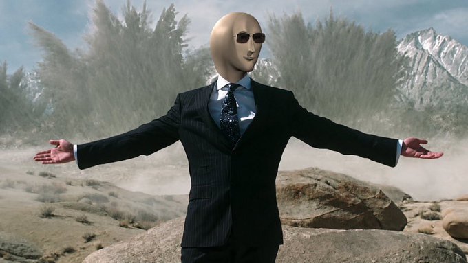 A surreal image of a bald mannequin-like figure in a dark pinstripe suit and sunglasses standing with arms outstretched in a desert landscape with dust clouds and mountains in the background.