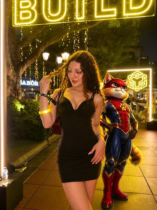 A photograph taken at night under a neon 'BULLD' sign, showing a young woman in a black dress standing next to a person or character in a Spider-Man-themed furry mascot costume.