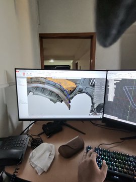 A person works at a dual-monitor setup showing 3D modeling software, with their hand on a keyboard, while a bright screen reflection creates the appearance of glowing eyes—fitting the "GM Dogs" and #raybanmeta theme of capturing a dog's-eye perspective of someone working.