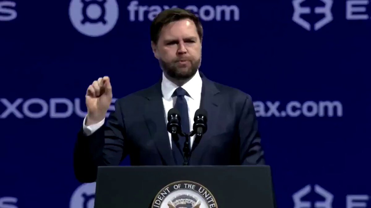 The image shows a man wearing a suit standing at a podium, giving a speech or presentation. The text in the image reads "CRYPTO IS HERE TO STAY VP Vance confirms: Bitcoin and digital assets are now mainstream economy. No more looking back!". This statement suggests that the man is discussing the rise of cryptocurrency and its impact on the economy.