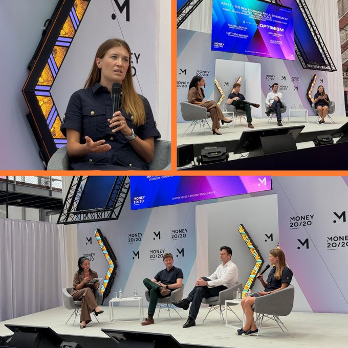 The image shows a group of people sitting around a table, engaged in conversation. There are four chairs visible in the scene, with two people seated on each chair. The individuals appear to be discussing various topics or sharing ideas. The backdrop features a large screen displaying information related to money and optimism, possibly indicating that they are at an event or gathering focused on financial matters.