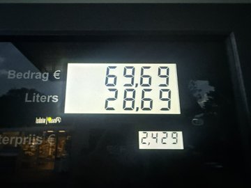An illuminated fuel station price display showing 'Bedrag € 69.69' and 'Liters 28.69' on a SunnyMobil sign.