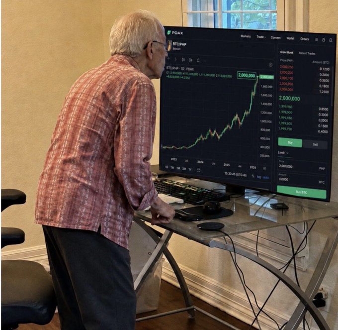 An elderly man stands hunched over a trading setup on a glass desk, intently watching a PDAX chart showing BTC/PHP Bitcoin price soaring to $2,000,000 in PH Peso, perfectly capturing the meme's lament of an investor whose $20,000 buy limit was never filled as Bitcoin rallied relentlessly to seven figures.