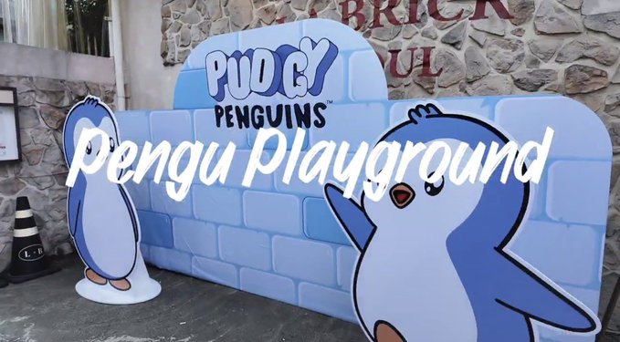 A colorful "Pudgy Penguins Playground" sign featuring two cartoon penguin characters stands against a stone brick wall, promoting the popular NFT collection's physical community experience. The playful display reflects Pudgy Penguins' expanding real-world presence beyond the digital space, complementing the post's celebration of the project's strong community and ecosystem.