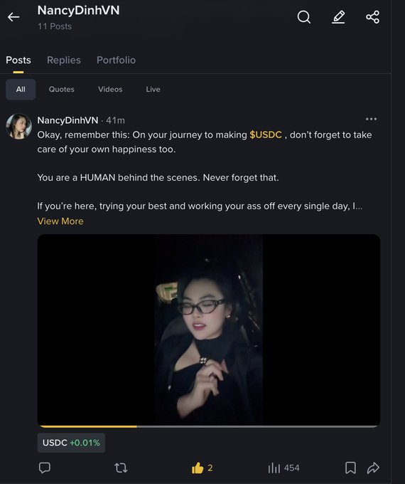 A screenshot of user NancyDinhVN's posts page shows a post reminding followers to take care of their happiness while working toward $USDC, accompanied by a video thumbnail of a woman wearing glasses.
